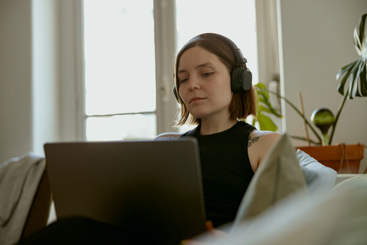 Woman wearing headphones and using a laptop during an at-home EMDR session