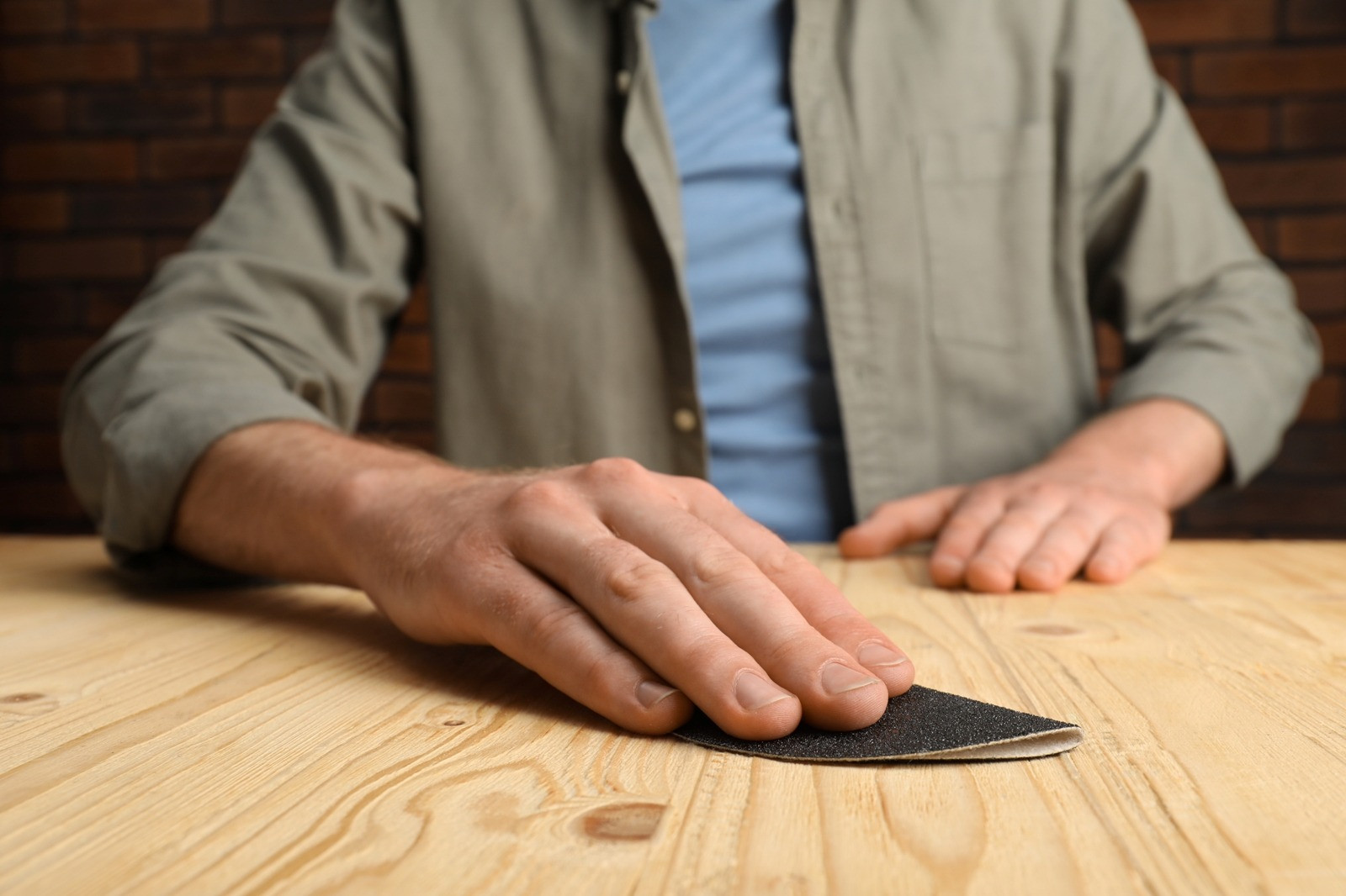 Close-up of a man's hands resting on a wooden table, with one hand touching a textured surface, illustrating physical sensations and body awareness during EMDR therapy.