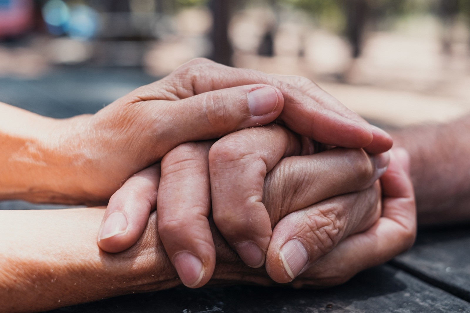 Close-up of two people holding hands in a supportive gesture.