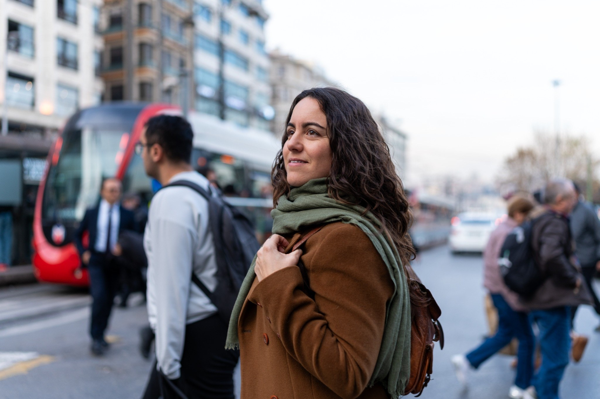 Woman standing on a busy city street near public transportation