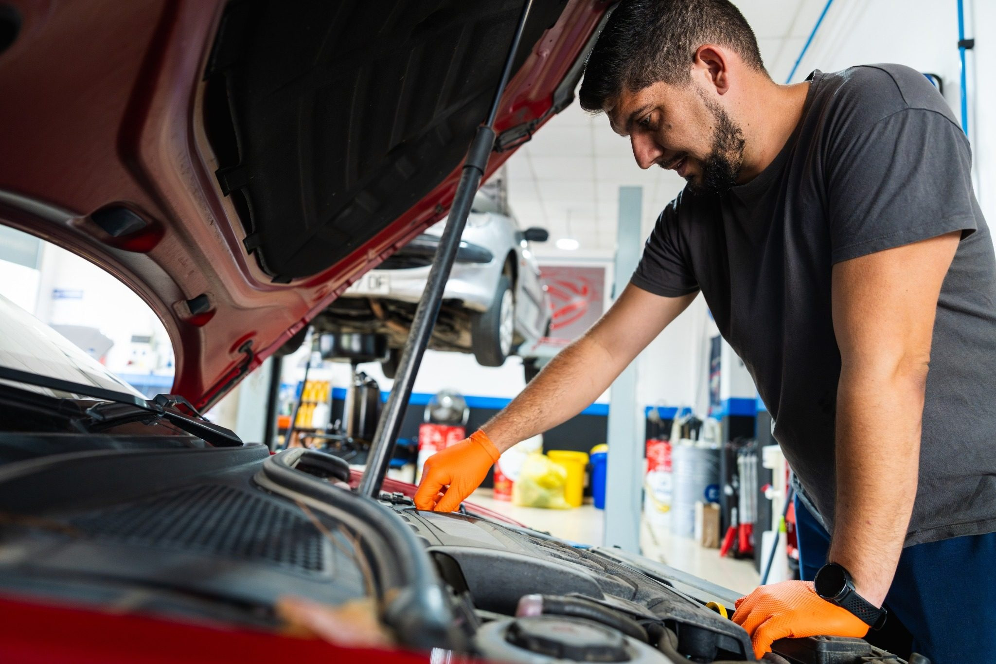 Auto mechanic working under the hood of a car in a repair shop