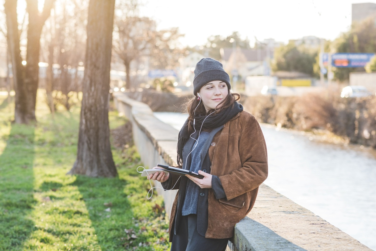 Woman outdoors wearing earphones and holding a tablet, illustrating flexible EMDR scheduling and self-guided use.