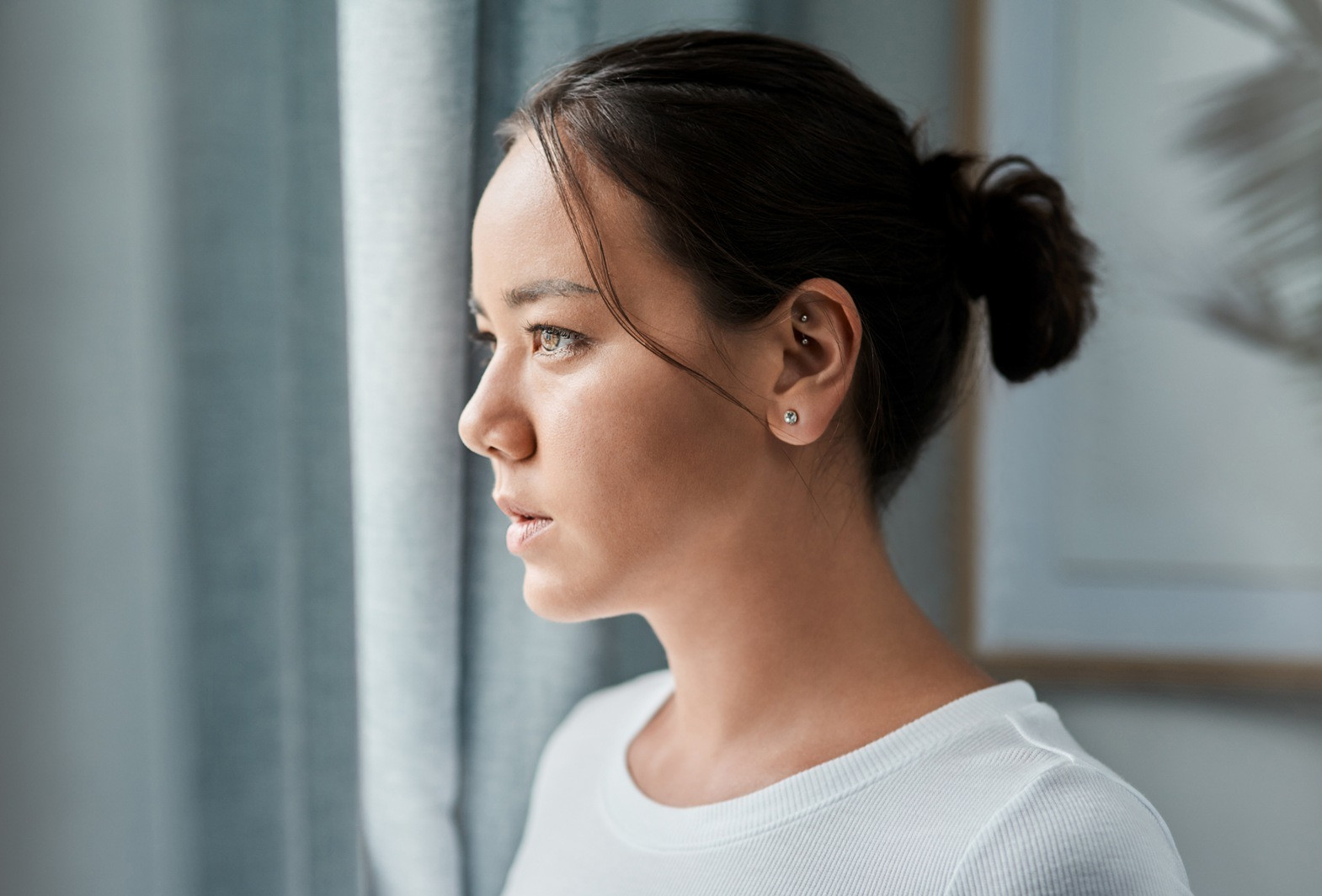 Woman looking thoughtfully out a window, representing reflection after a self-guided EMDR session before bed.