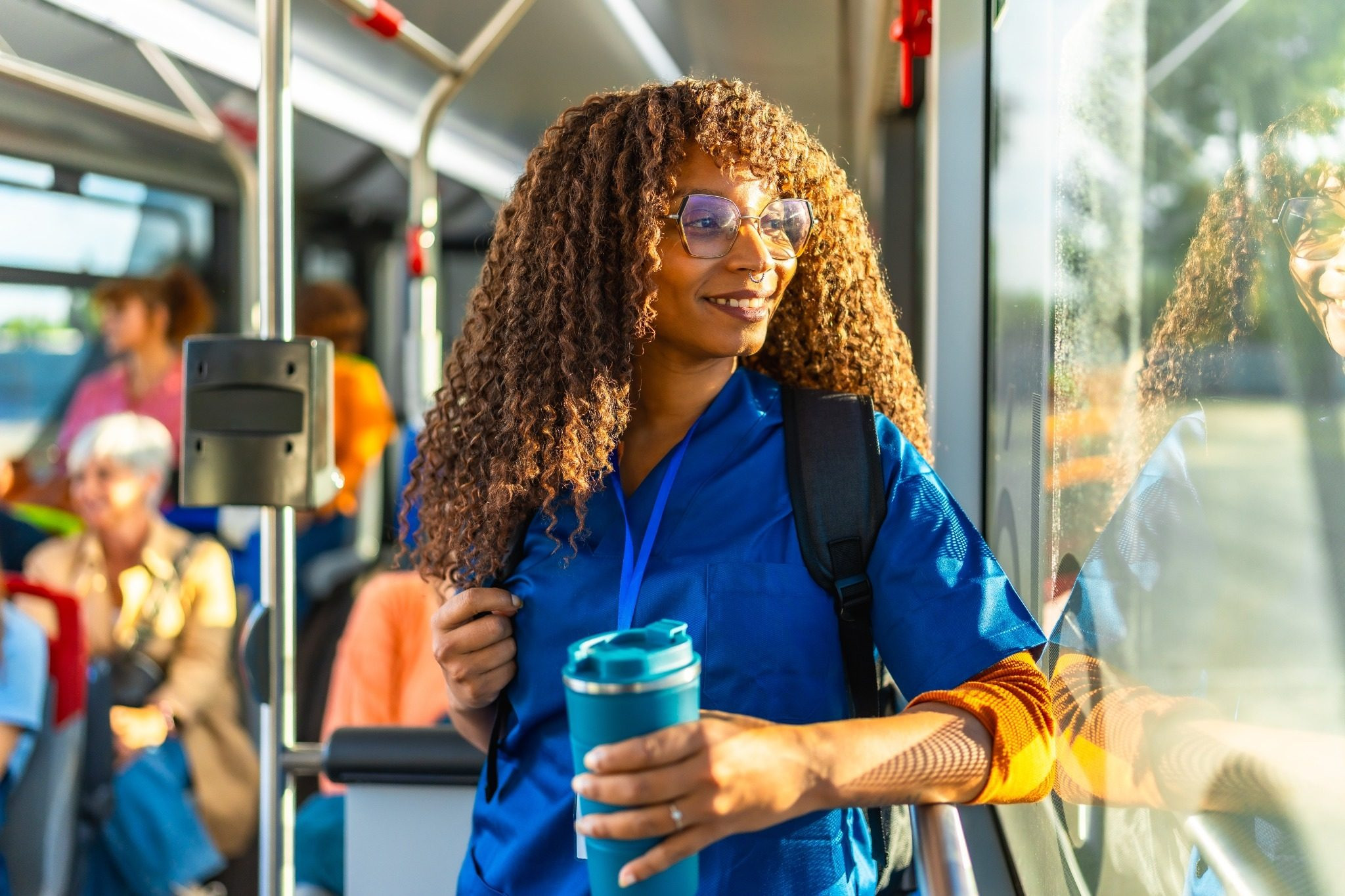 Woman wearing blue scrubs riding public transportation