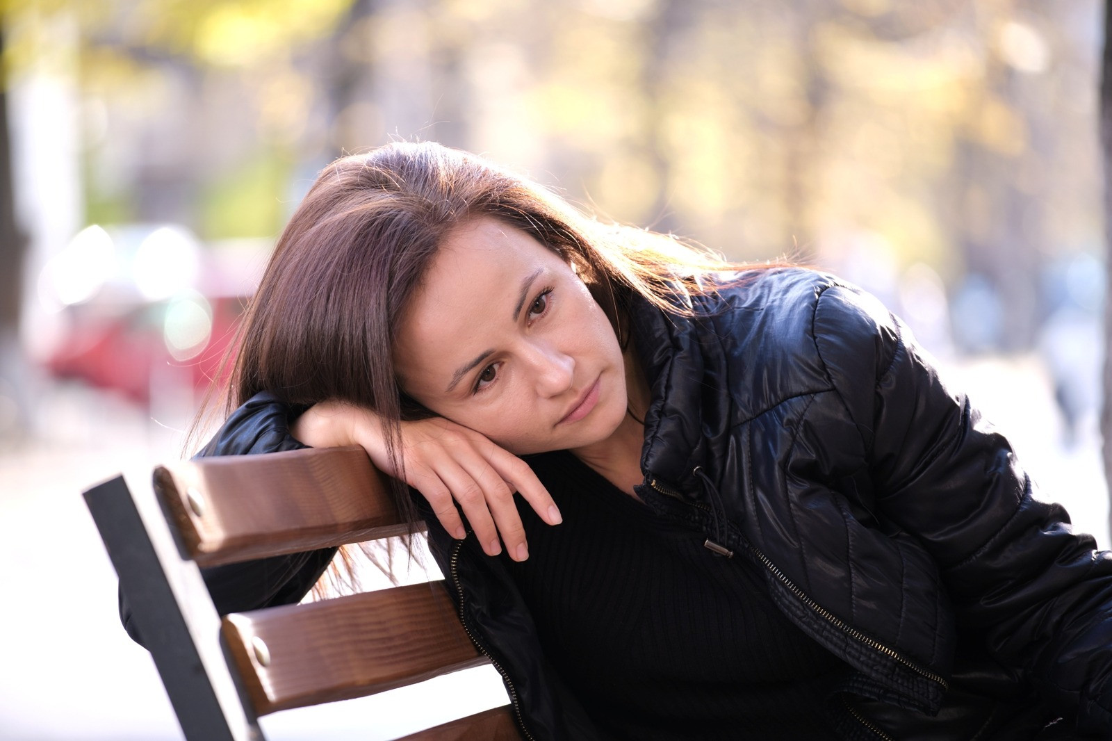 Woman resting thoughtfully on a park bench outdoors