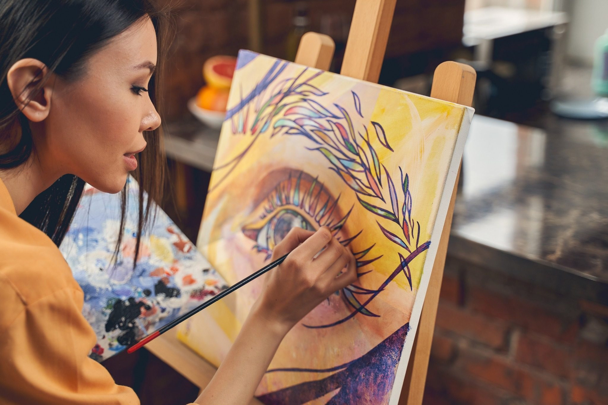 Woman painting a colorful eye on canvas at an easel