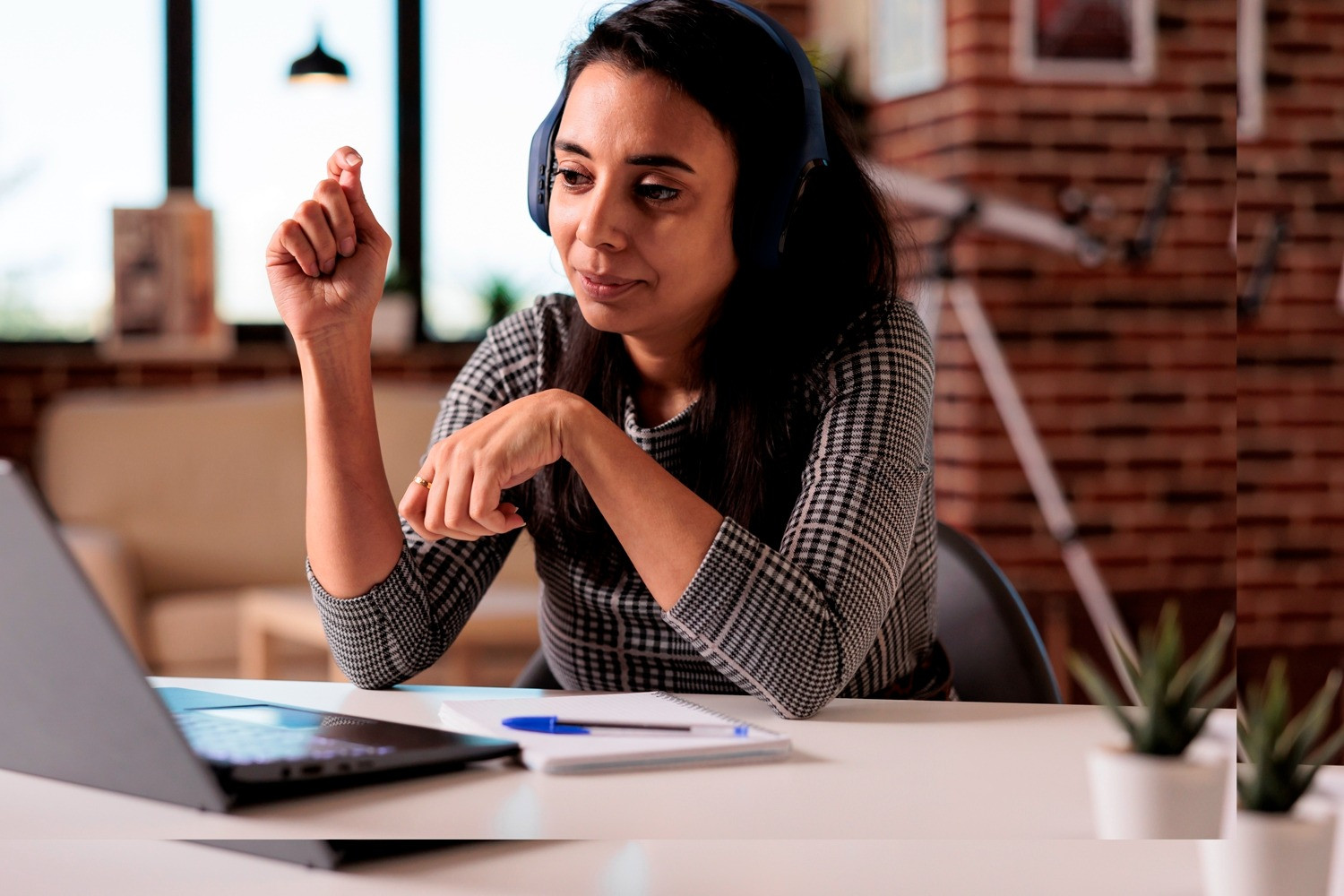 Woman wearing headphones while using a laptop for a self-guided EMDR session at home.