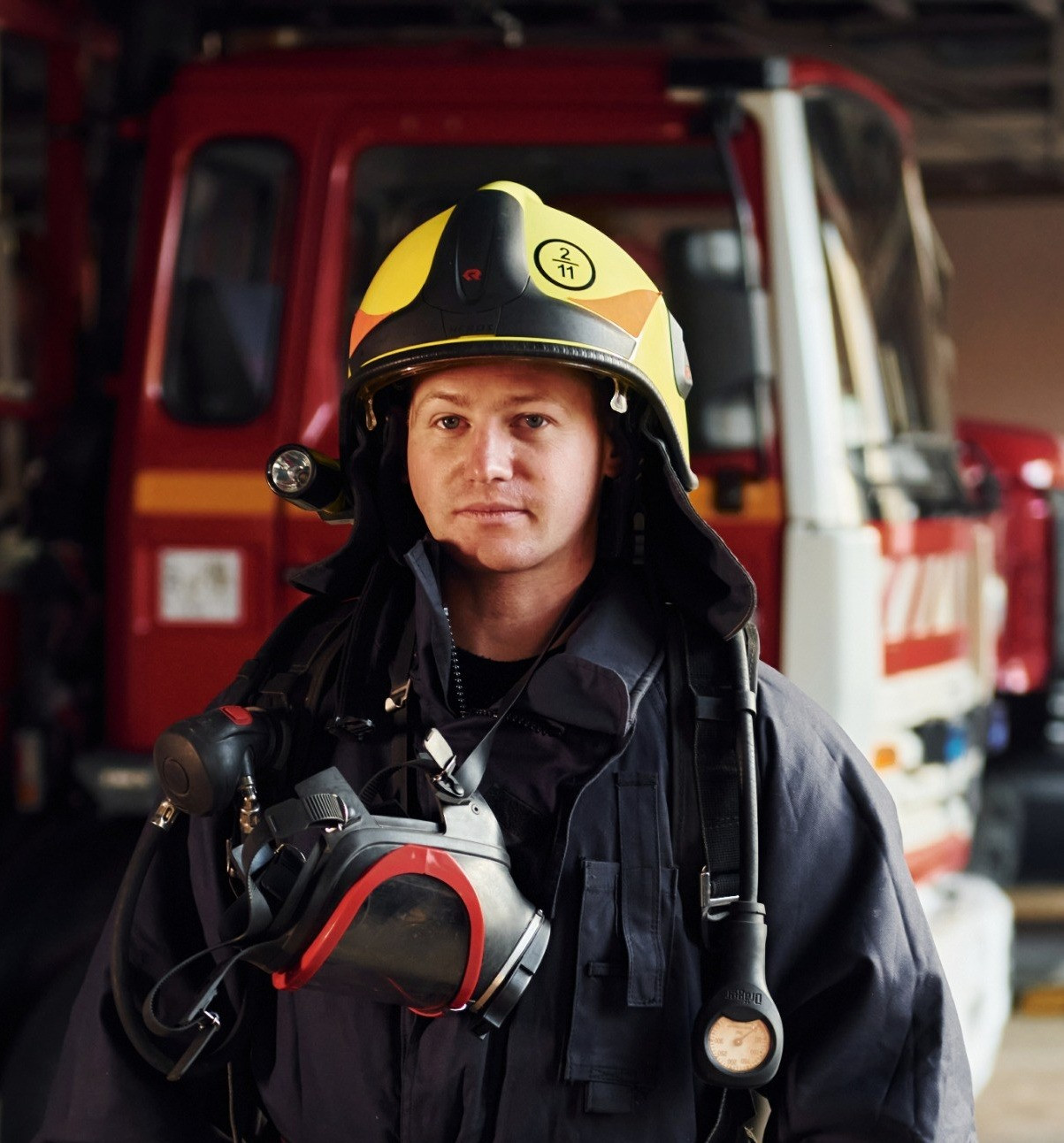 Firefighter in protective gear standing in front of a fire engine