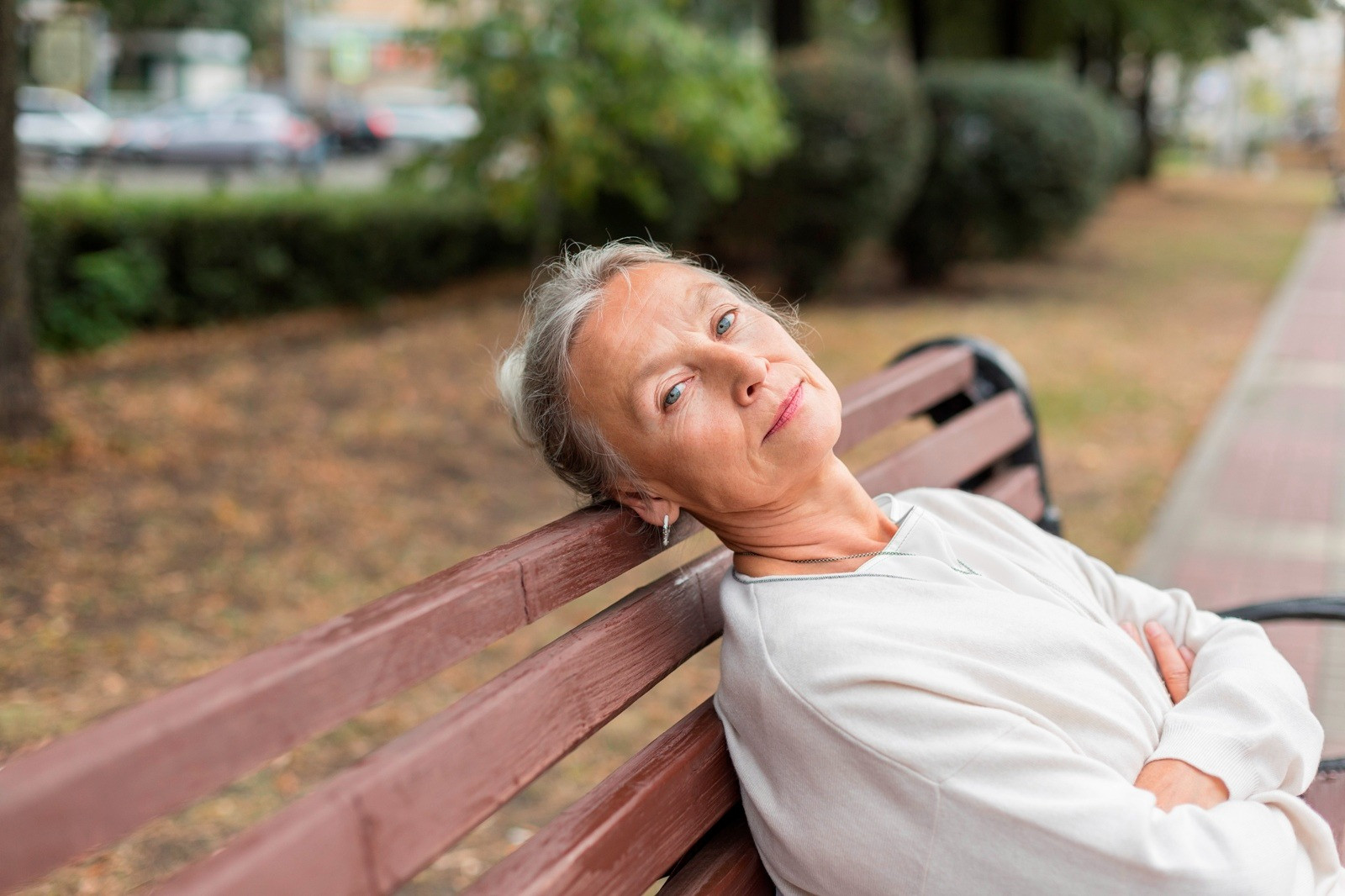 Older woman sitting calmly on a park bench, representing reflection and recovery after trauma.