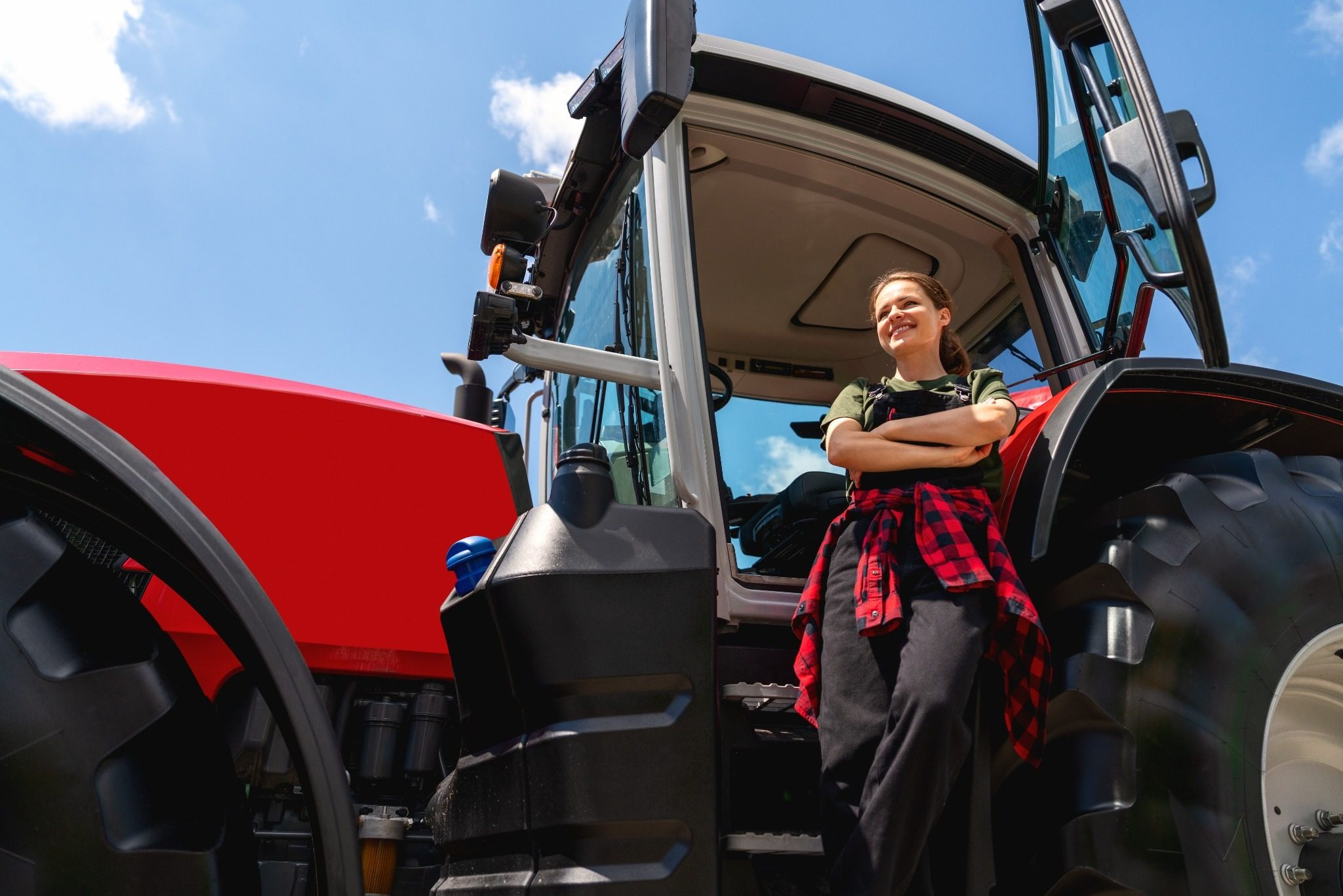 Woman standing beside a red tractor outdoors