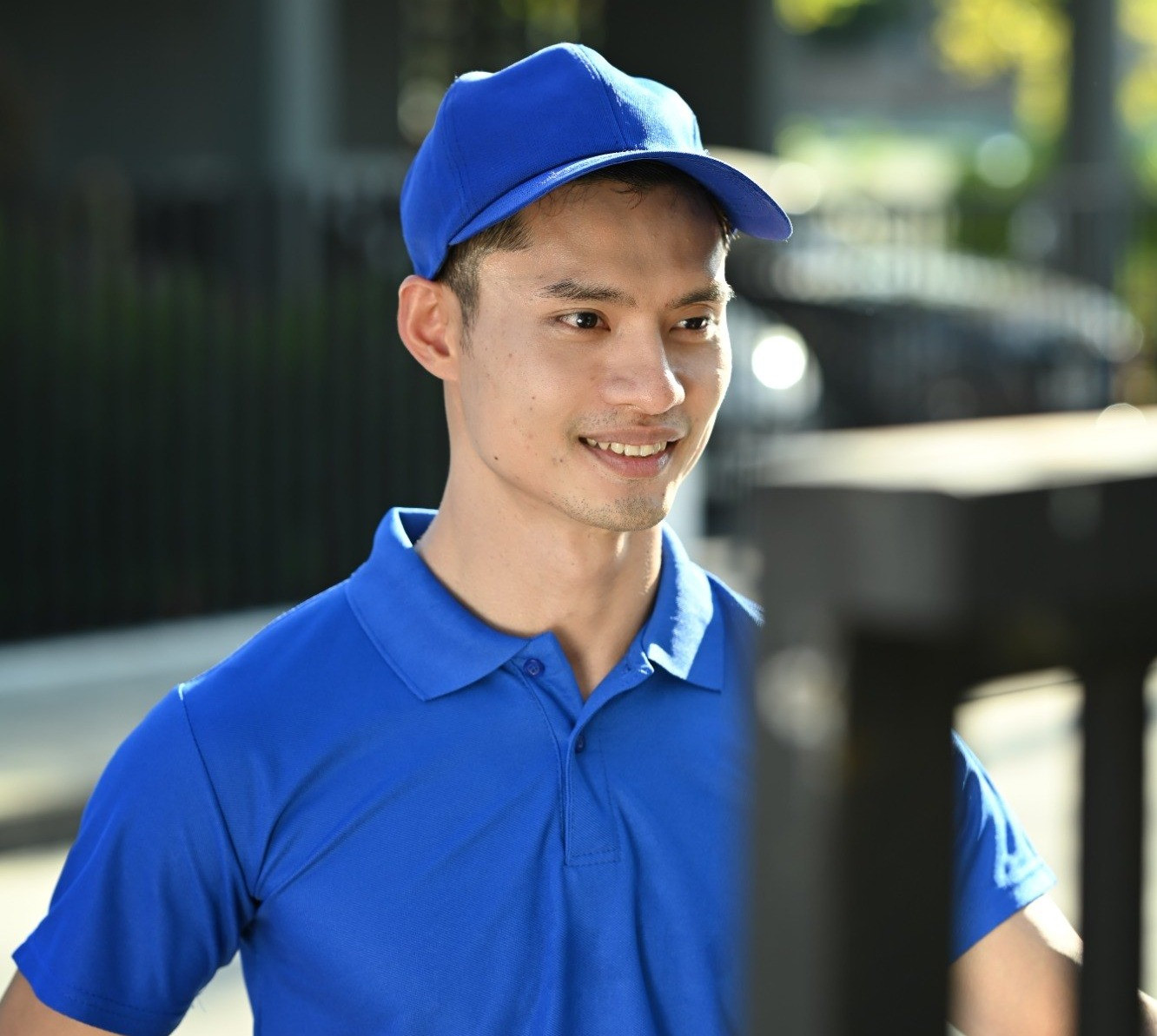 Delivery worker in a blue uniform holding a package while standing outdoors