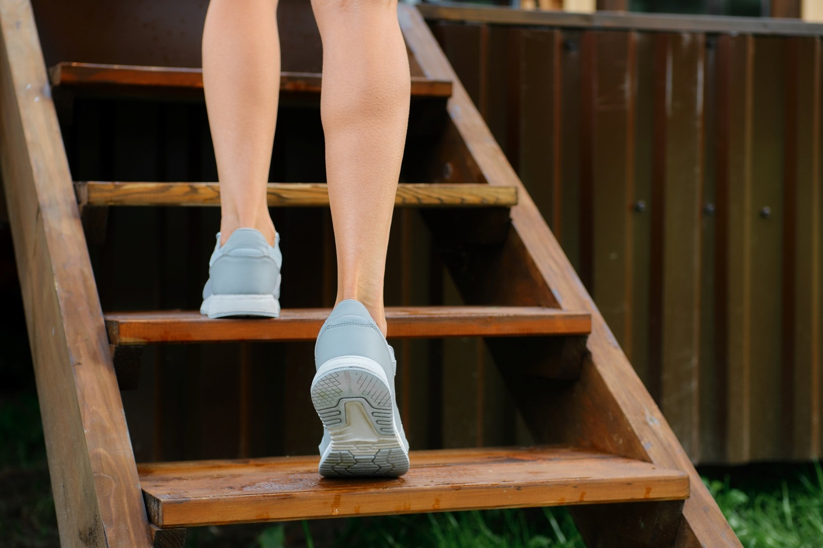 Close-up of a person wearing light blue sneakers walking up wooden stairs, representing personal choice, independence, and moving forward at one's own pace.