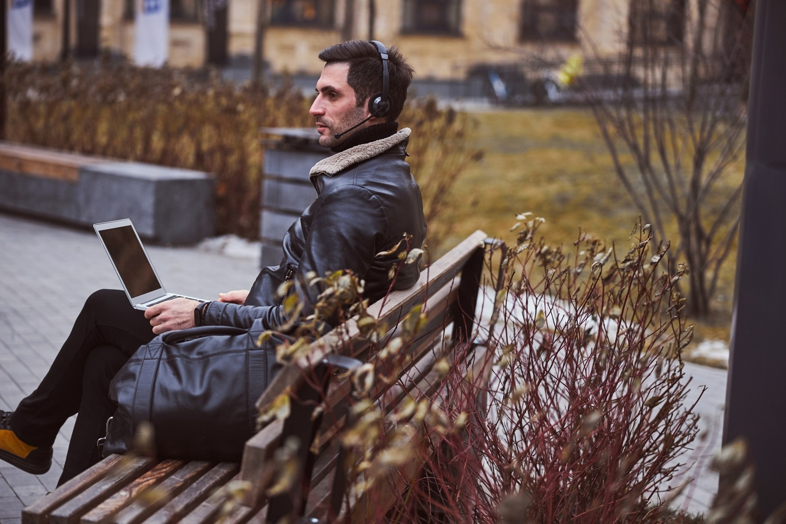 Man wearing headphones while sitting on a bench with a laptop, representing audio bilateral stimulation during EMDR.