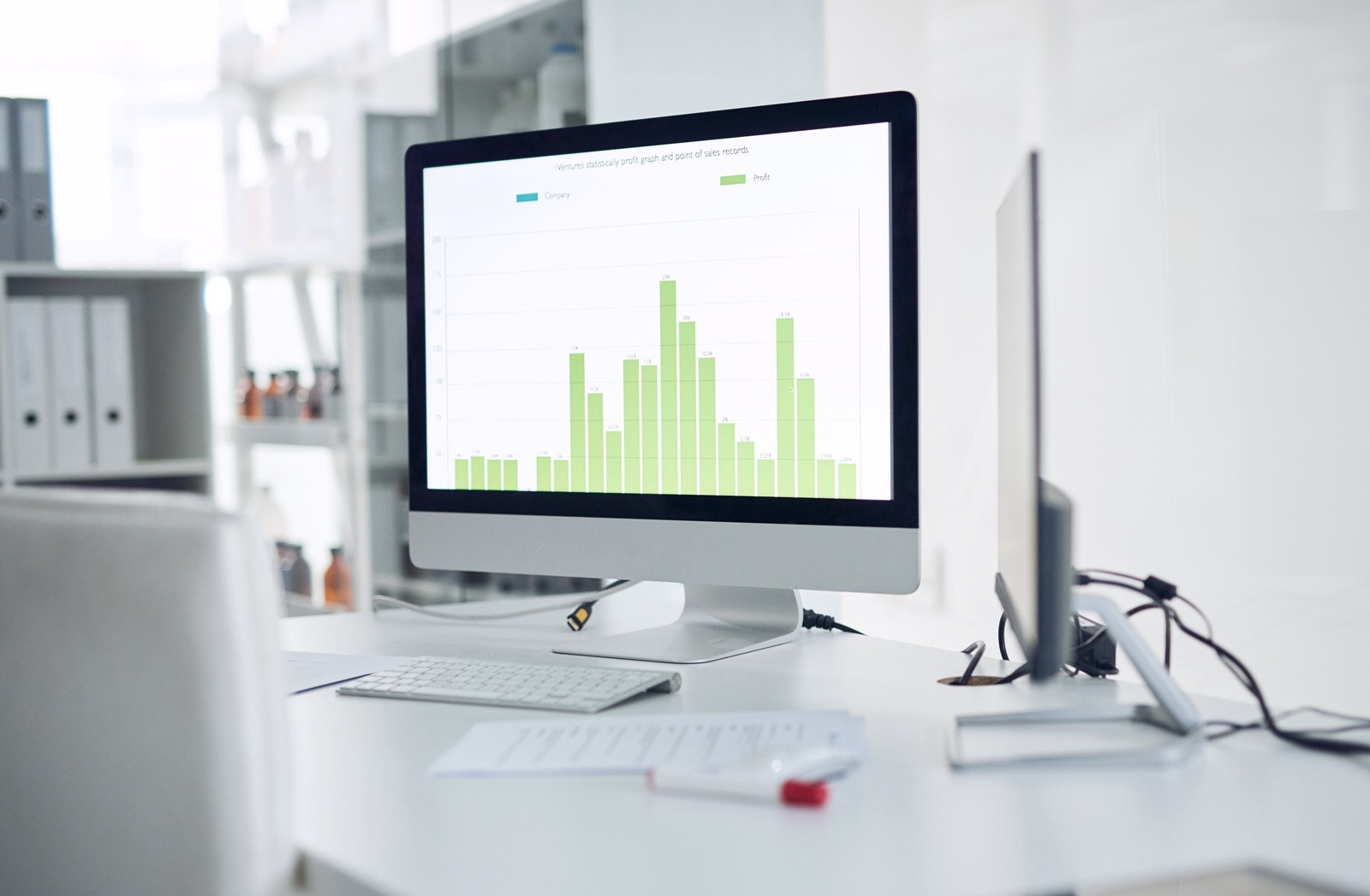 Computer monitor displaying a bar chart in a bright office workspace, representing the observation and tracking of changes over time.