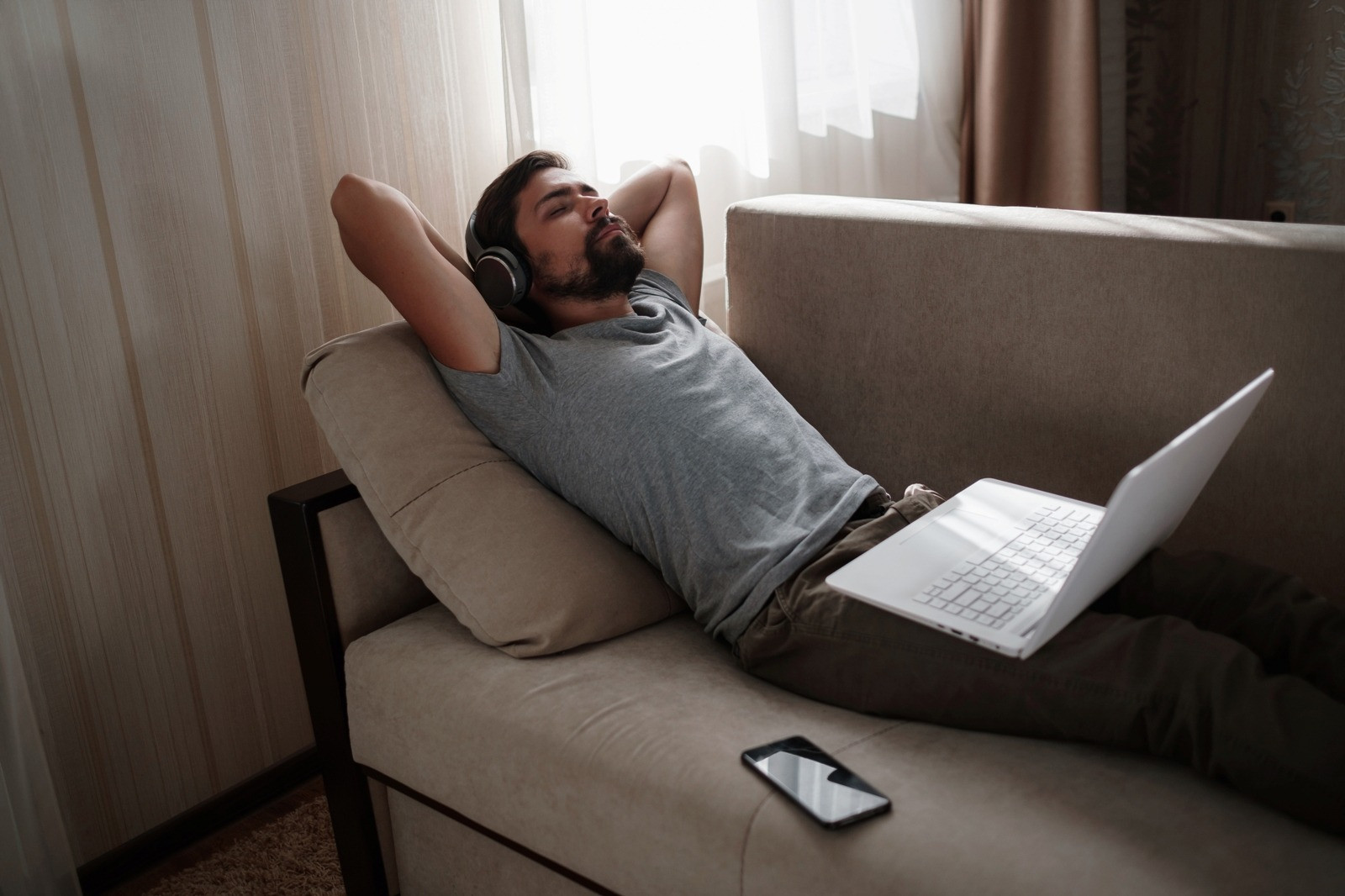 Man relaxing on a sofa with headphones and a laptop during a calm at-home EMDR exercise.