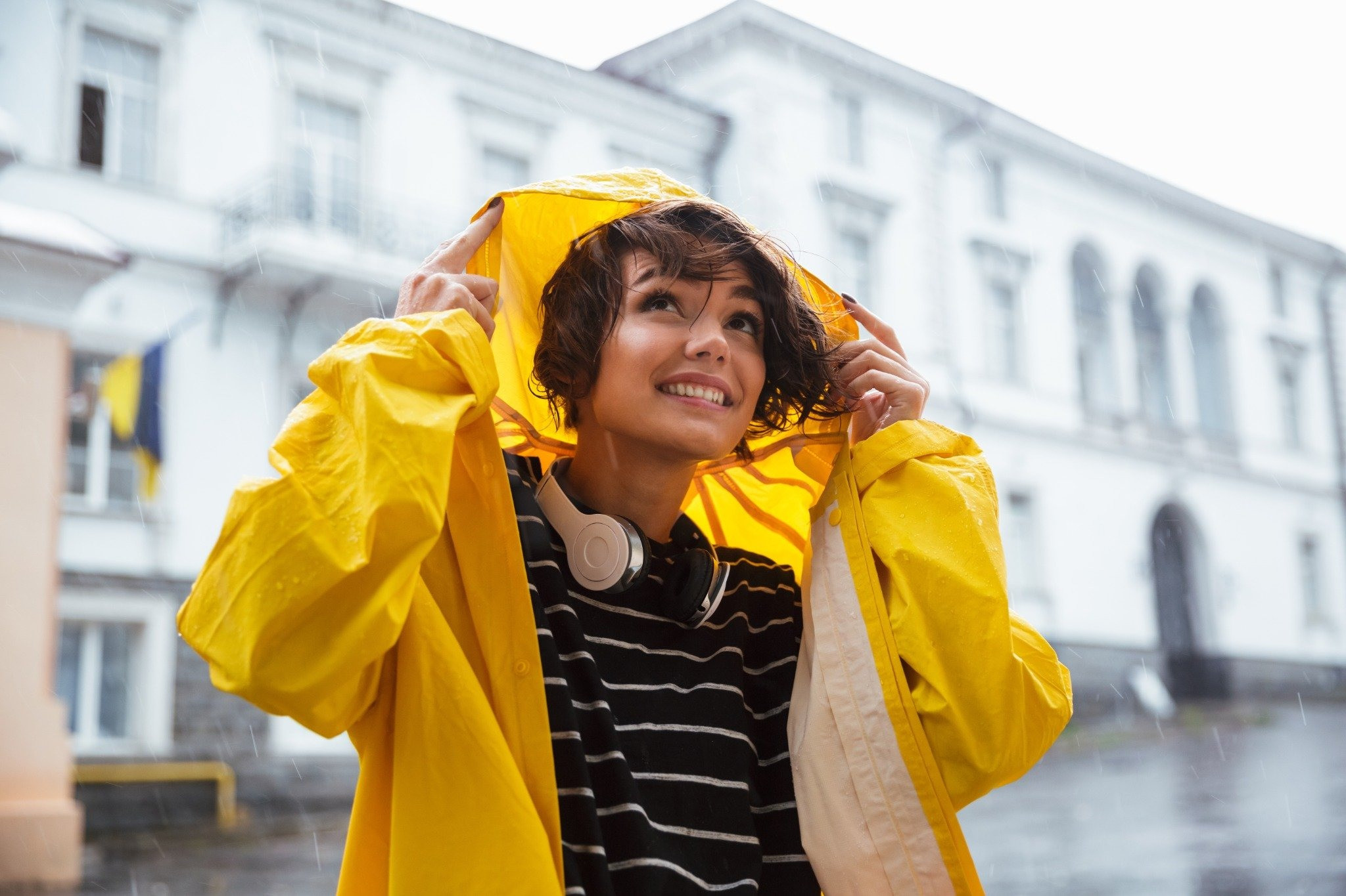 Woman in a yellow raincoat standing outdoors in the rain