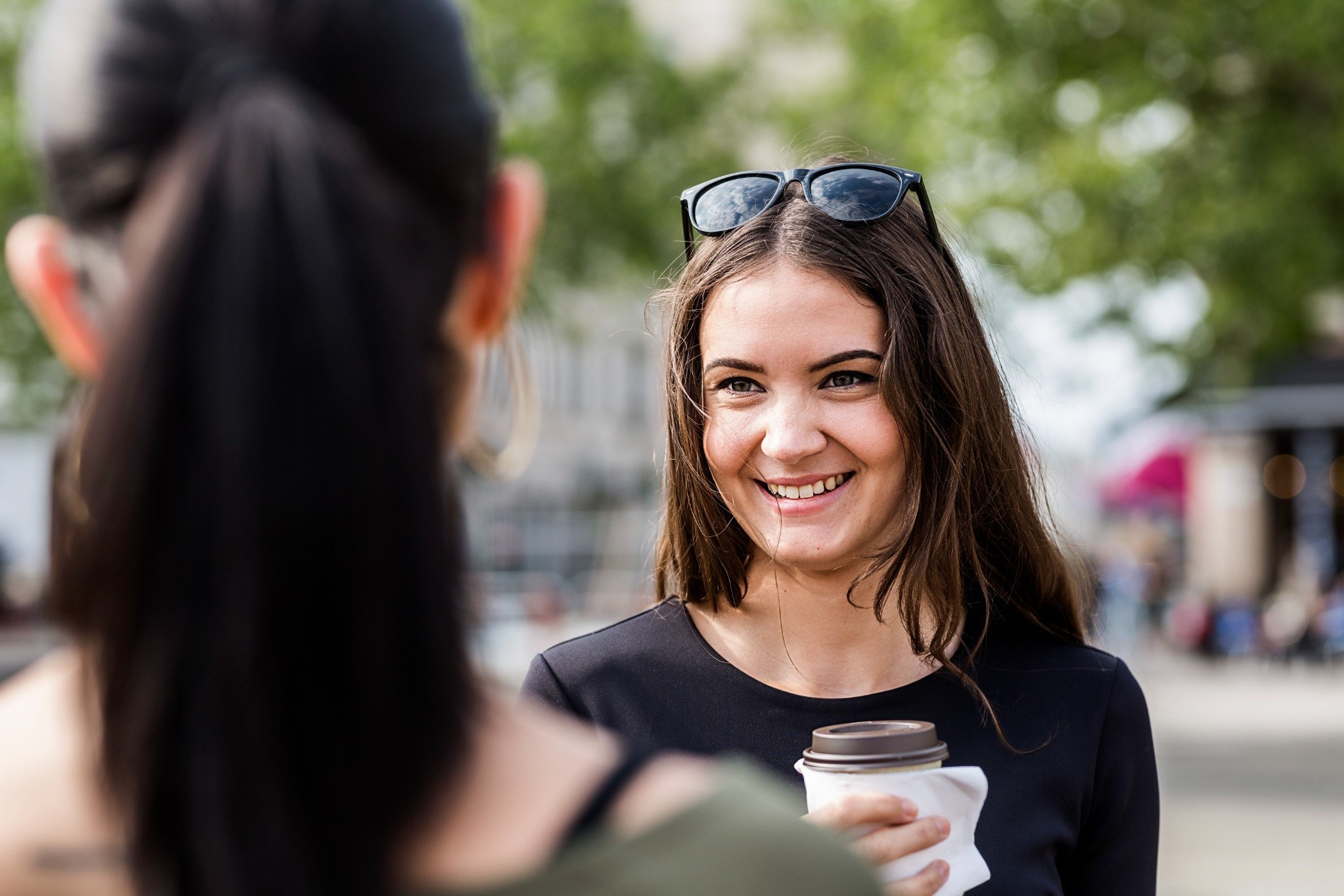 Woman smiling while talking with another person outdoors