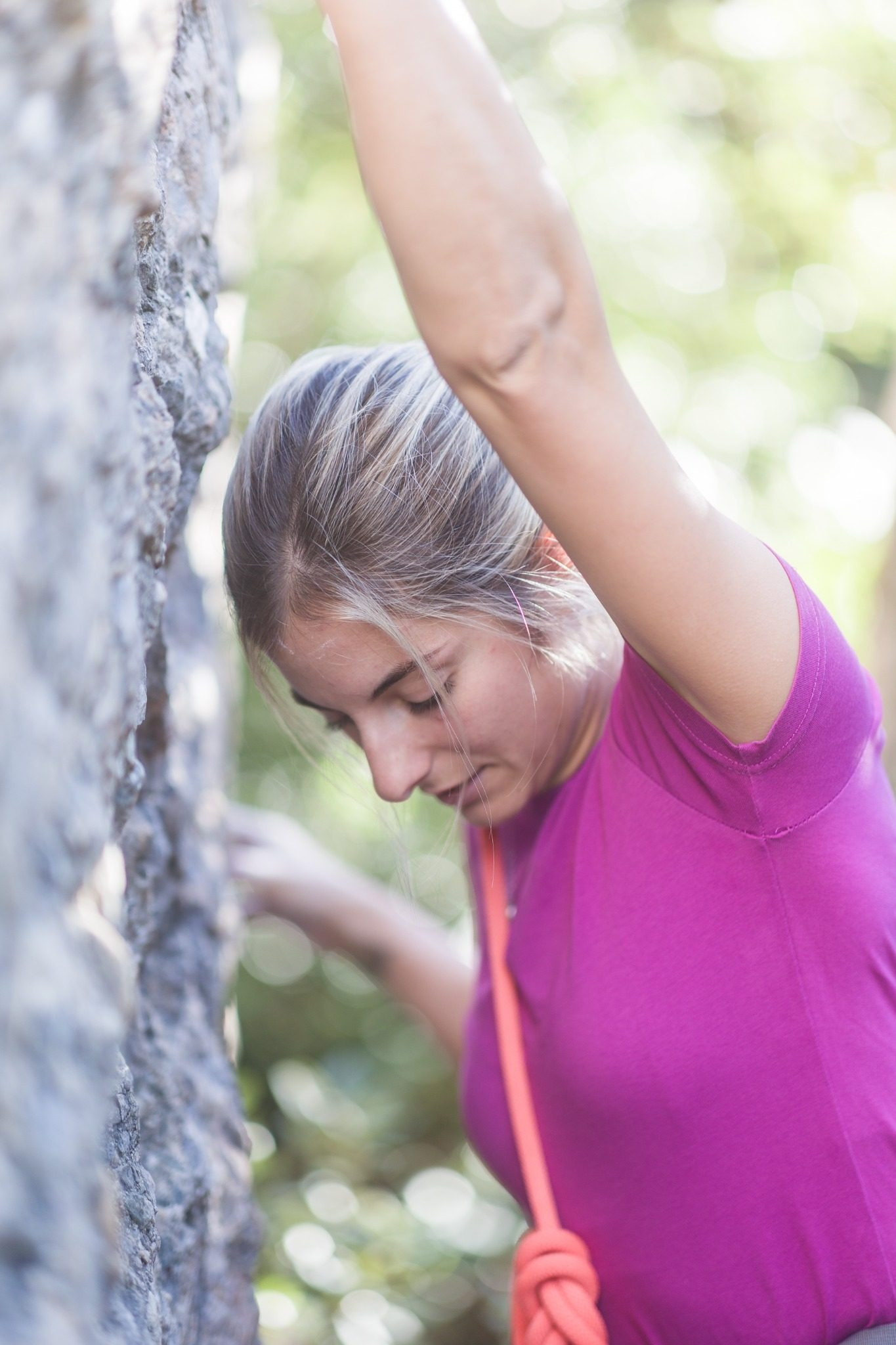 Woman rock climbing outdoors while holding onto a rock wall