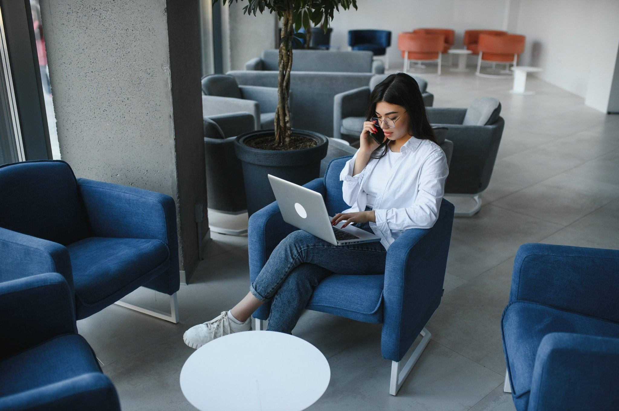 Woman sitting with a laptop while talking on the phone in a lounge