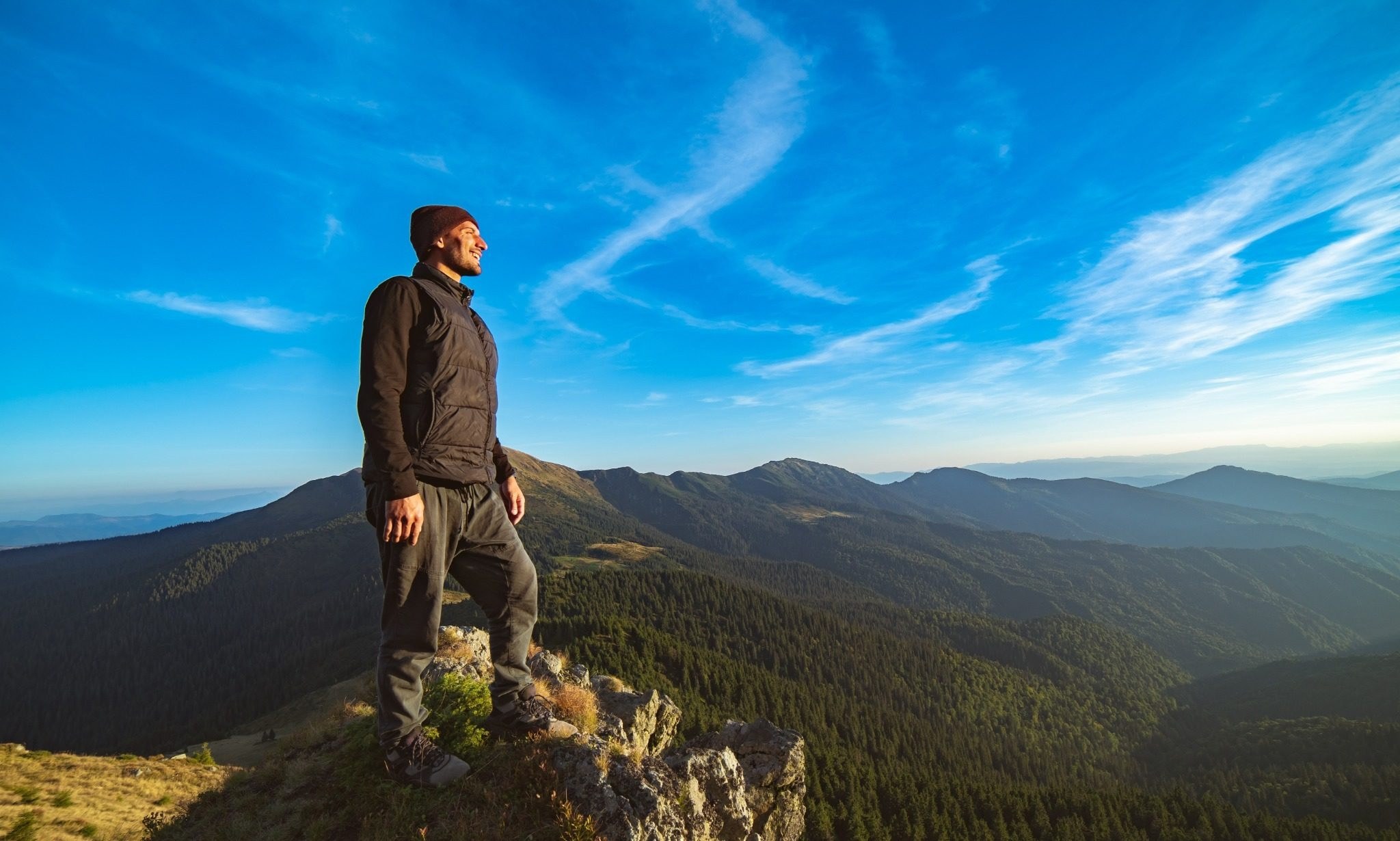 Man standing on a mountain overlooking a wide landscape