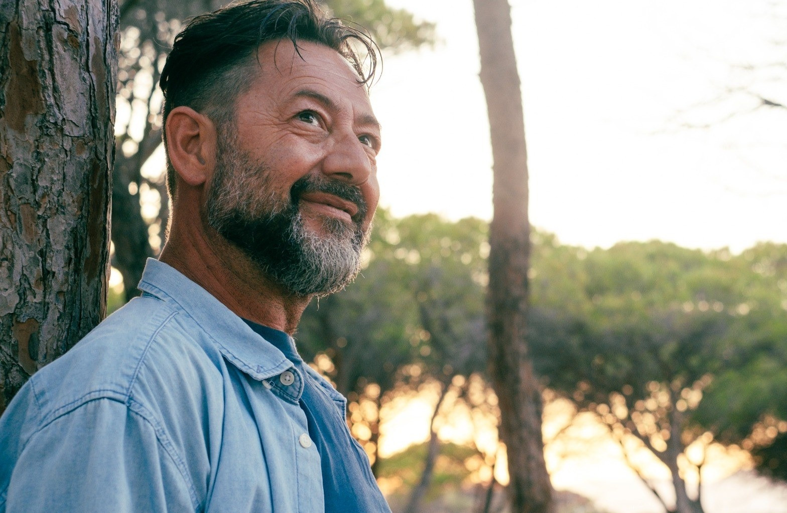 Man standing outdoors among trees at sunset