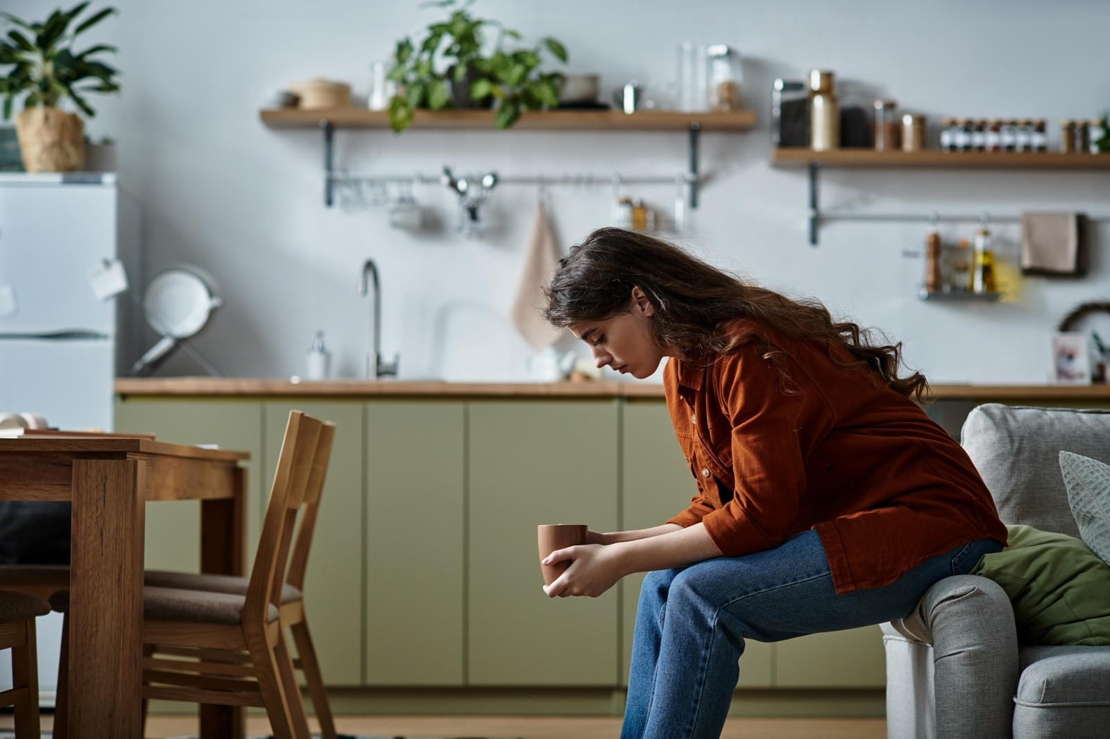 Woman sitting thoughtfully at home holding a cup, representing negative beliefs and self-reflection during EMDR.