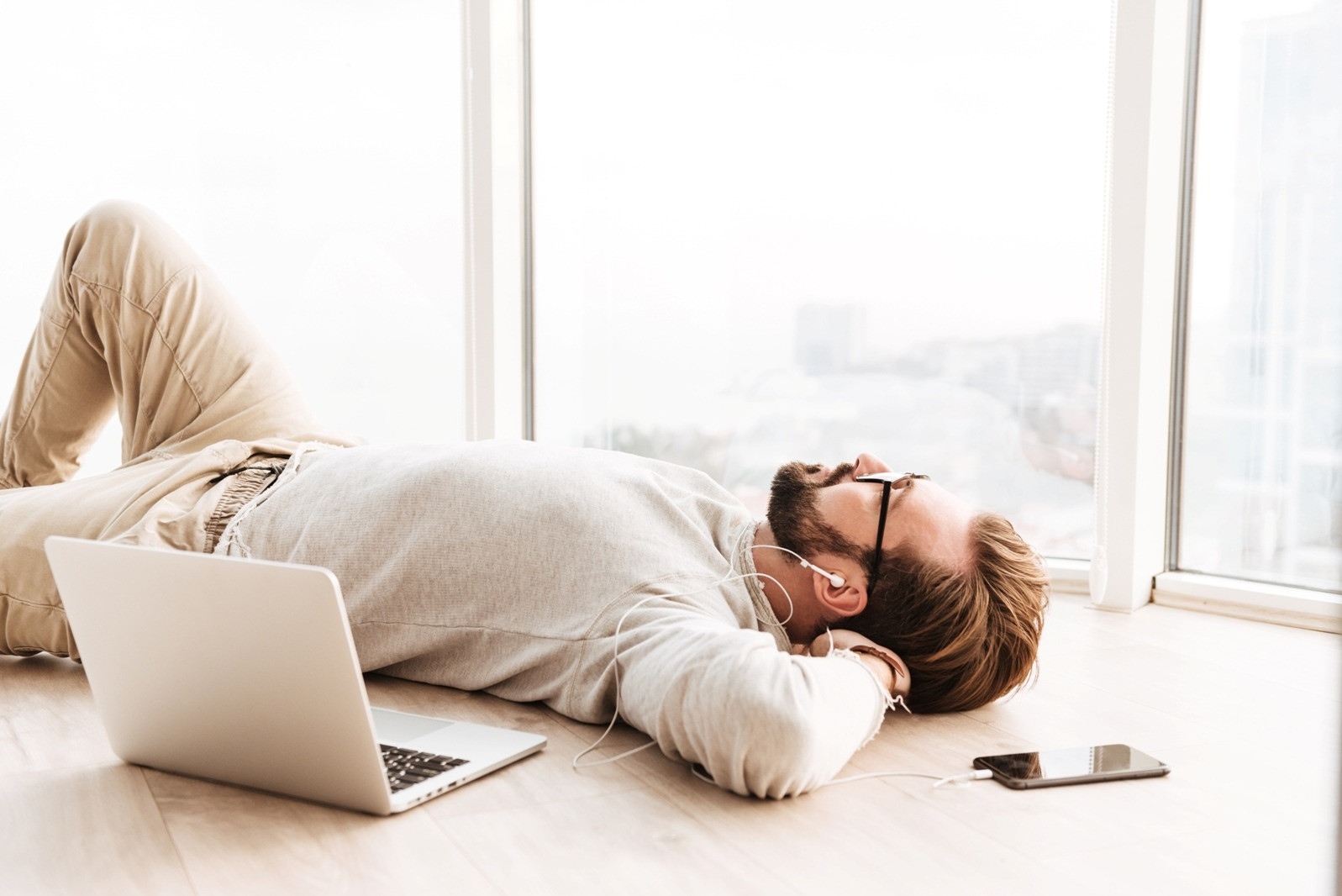 Man resting on the floor beside a laptop while wearing earphones, representing a break during a self-guided EMDR session.