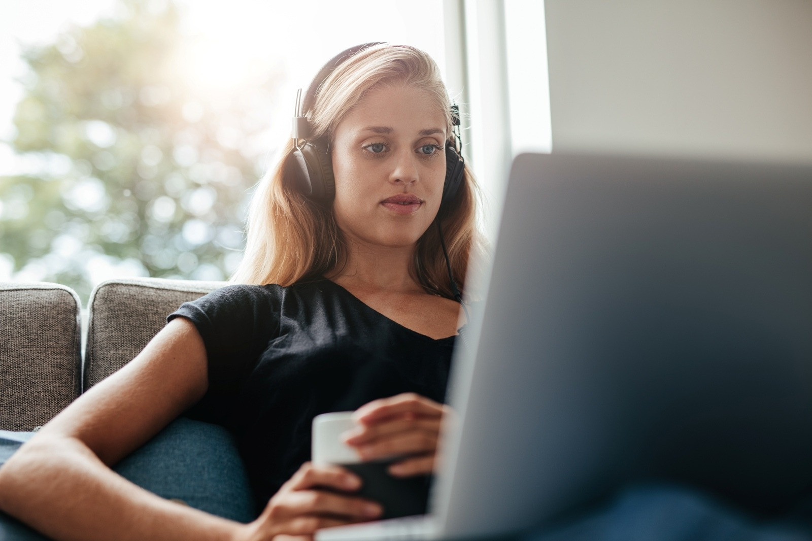Woman wearing headphones and using a laptop at home for an online EMDR session.