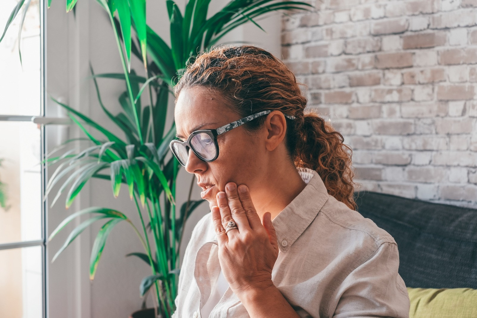 Woman sitting thoughtfully at home, reflecting on what to focus on during a self-guided EMDR session.