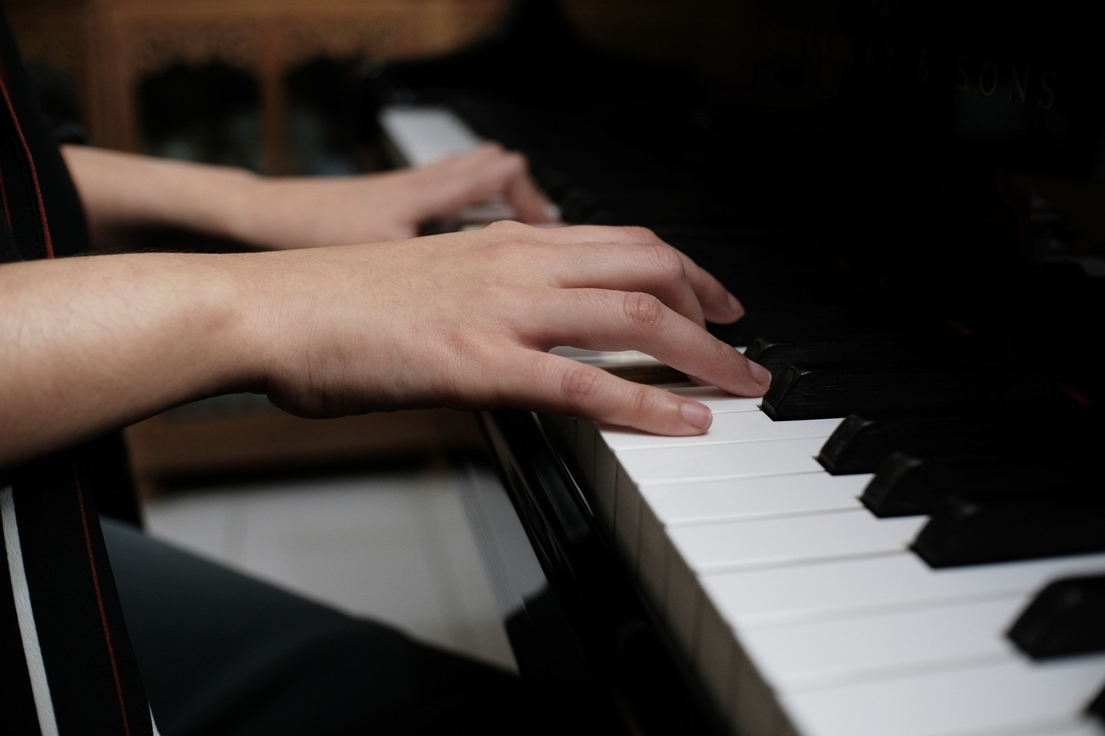 Close-up of a person's hands playing piano keys, illustrating sensory awareness and physical sensations that may arise during emotional experiences.