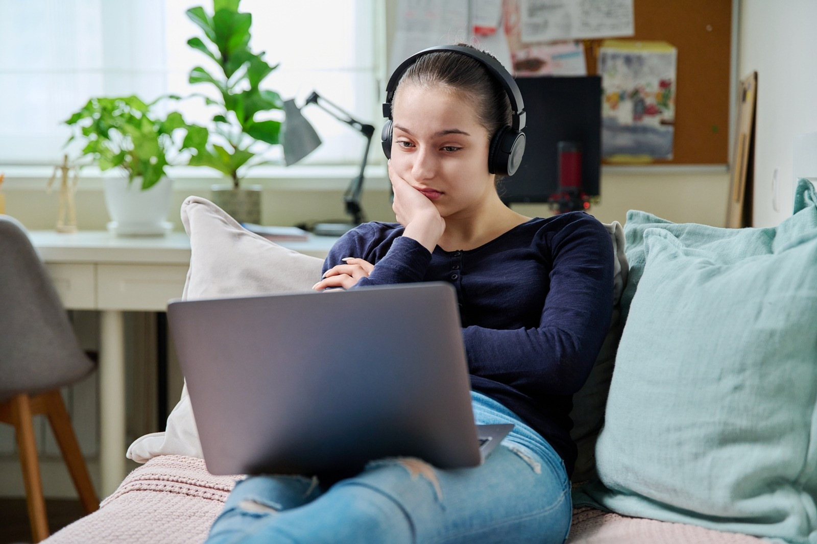Woman wearing headphones and using a laptop at home for an online EMDR session.
