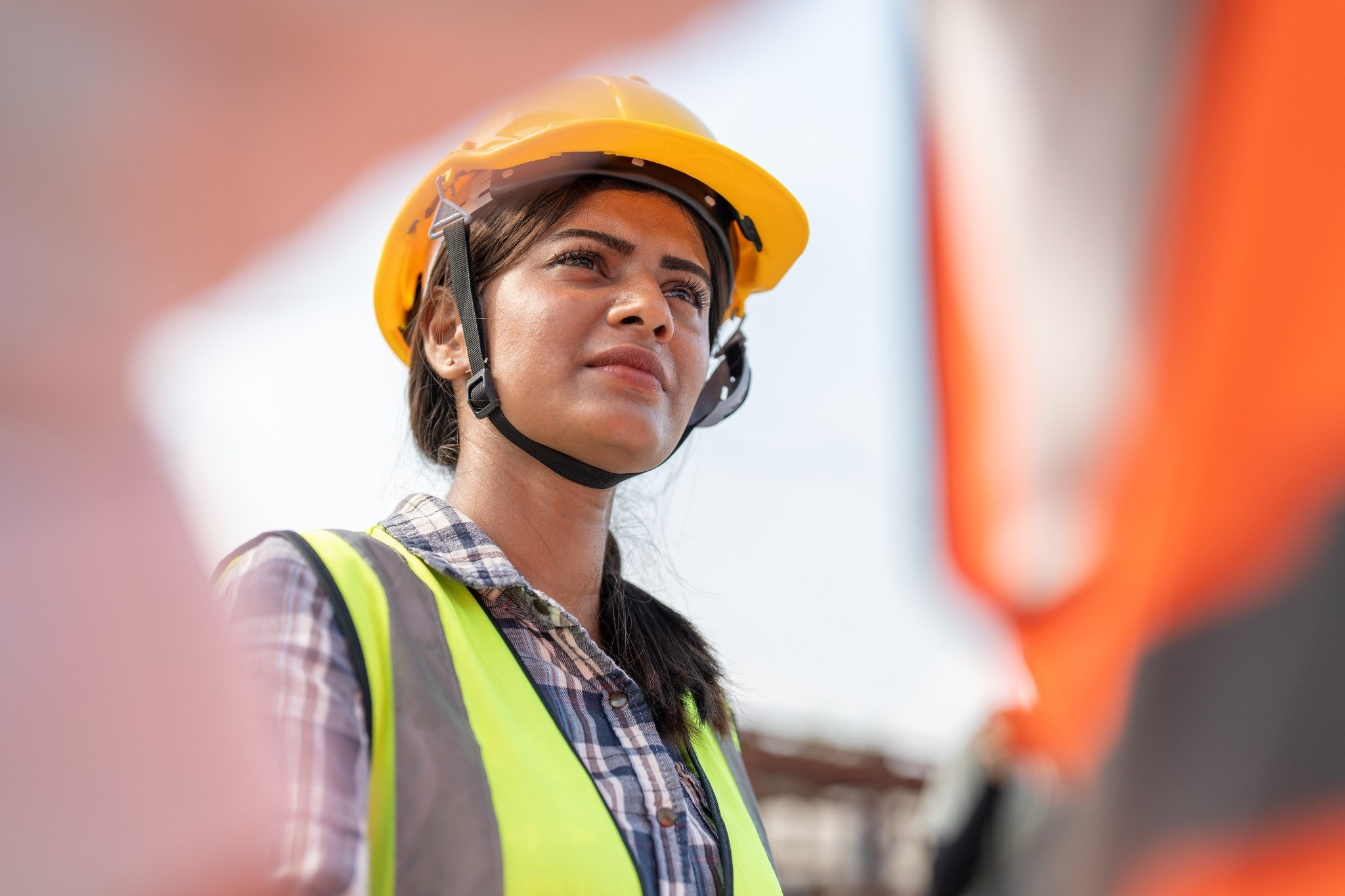 Woman wearing a hard hat and high-visibility safety vest outdoors