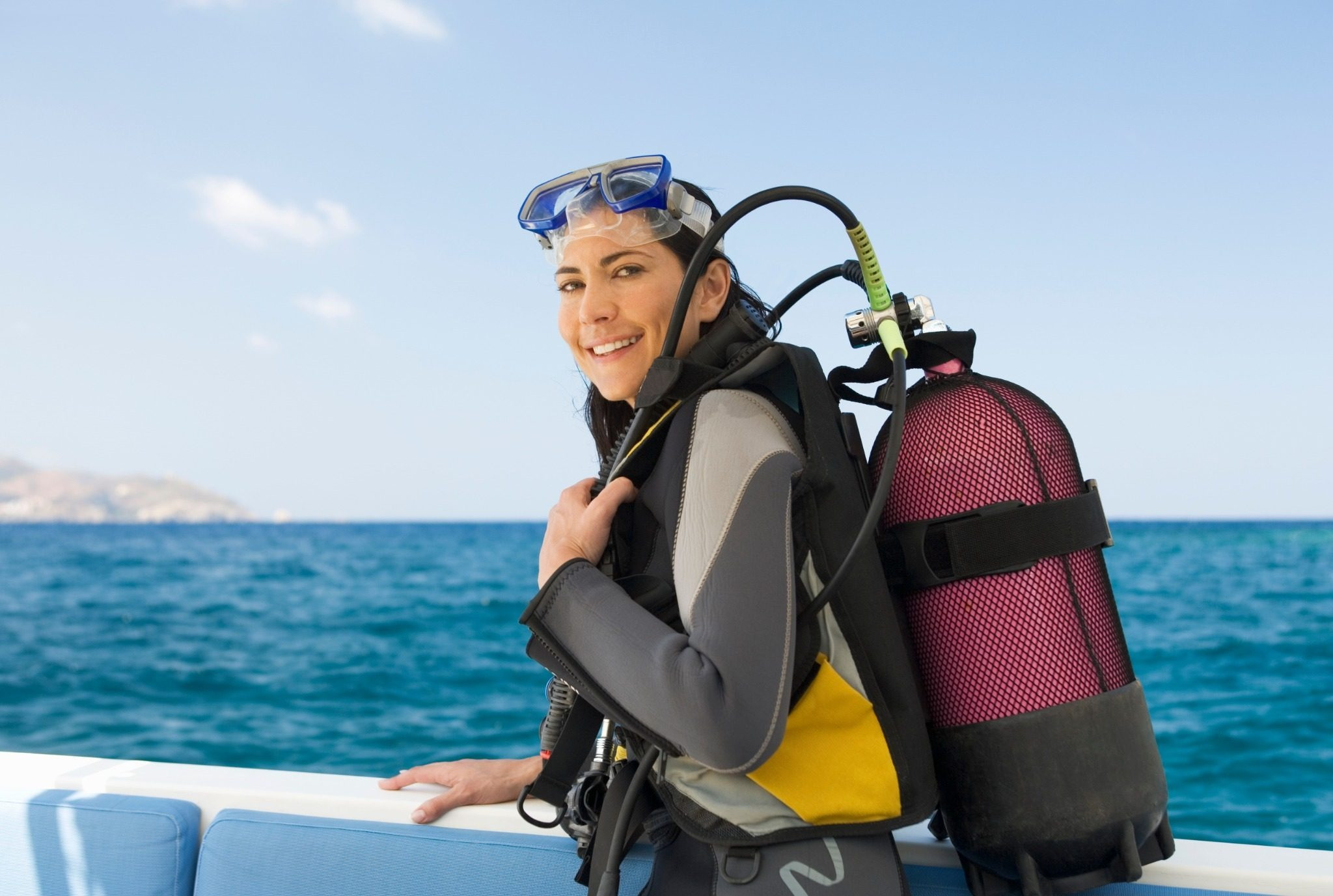 Woman wearing scuba gear preparing for a dive by the ocean
