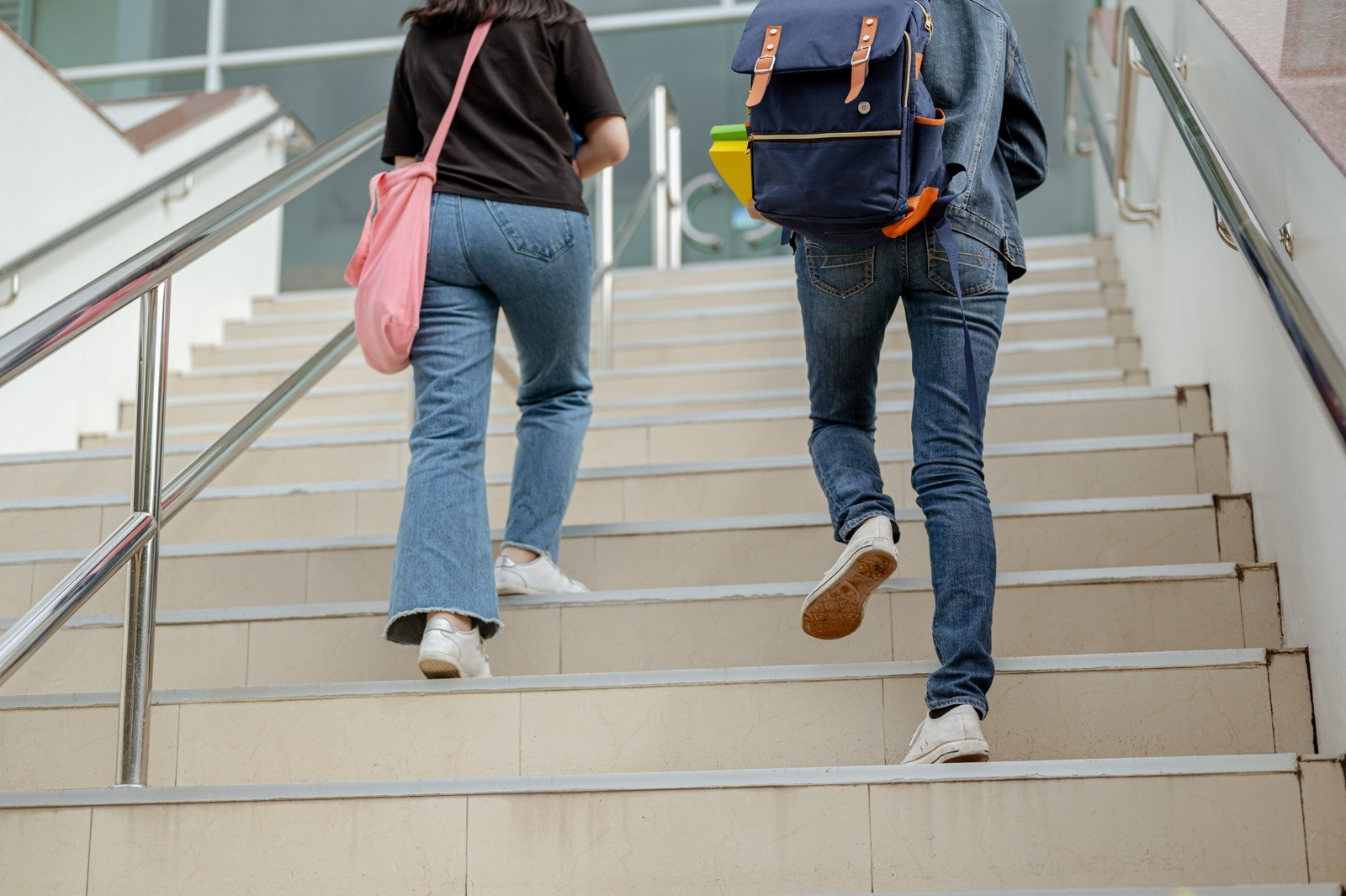 Two people with backpacks walking up a staircase, representing separation, transition, and moving forward.