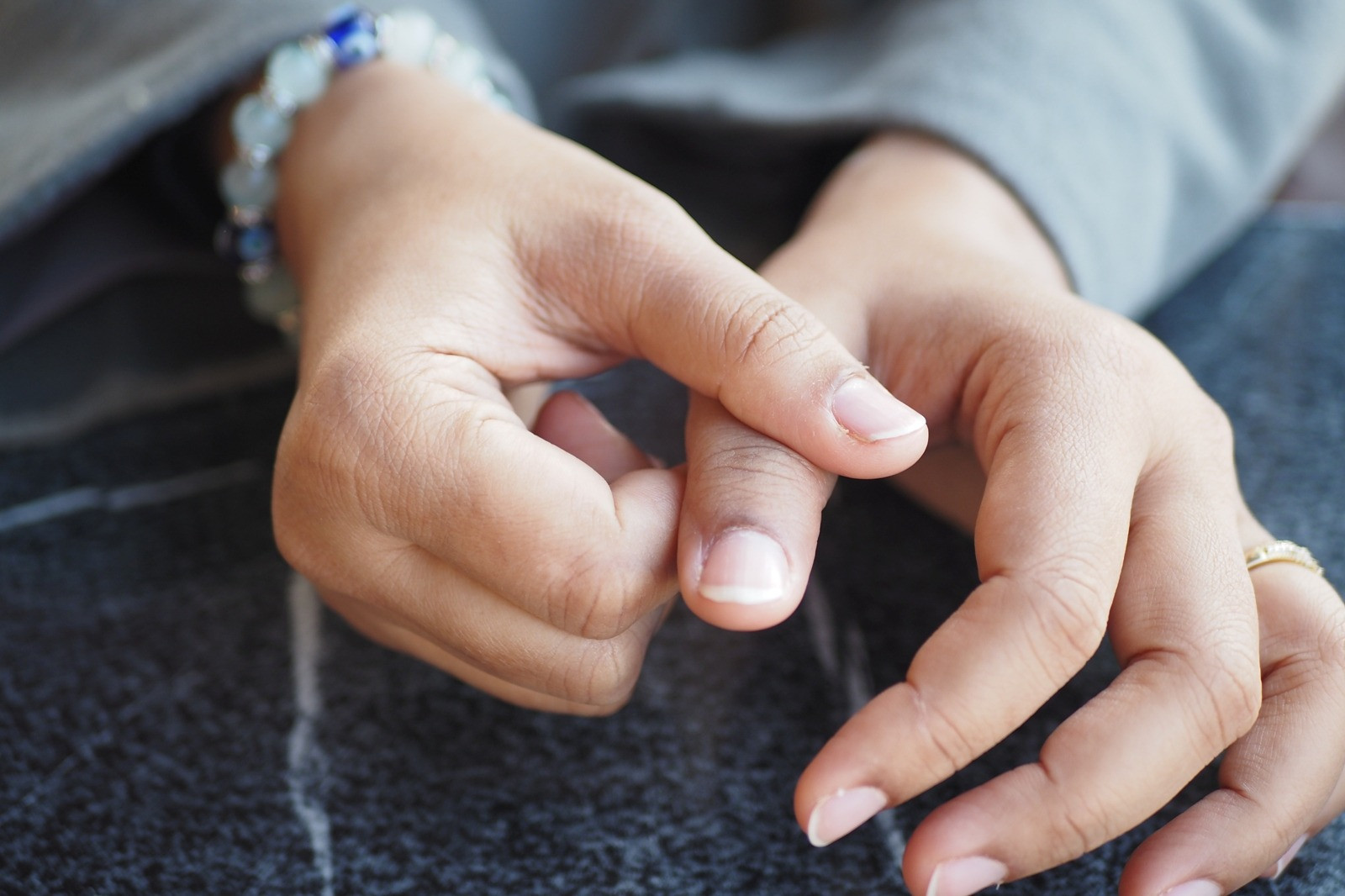 Close-up of a person's hands gently touching and holding their fingers together, illustrating subtle physical reactions and body awareness during emotional experiences.