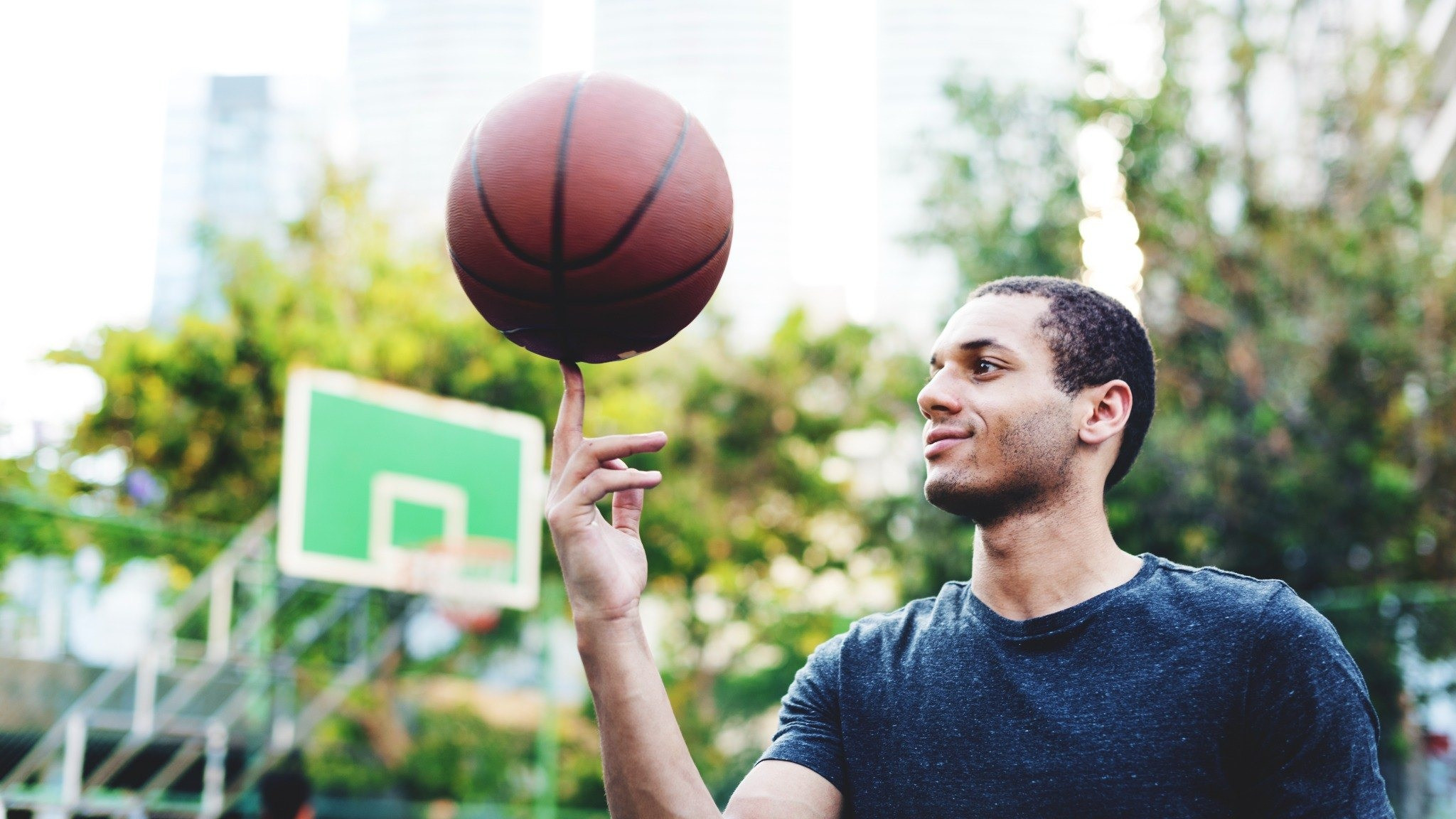 Man spinning a basketball on his finger outdoors