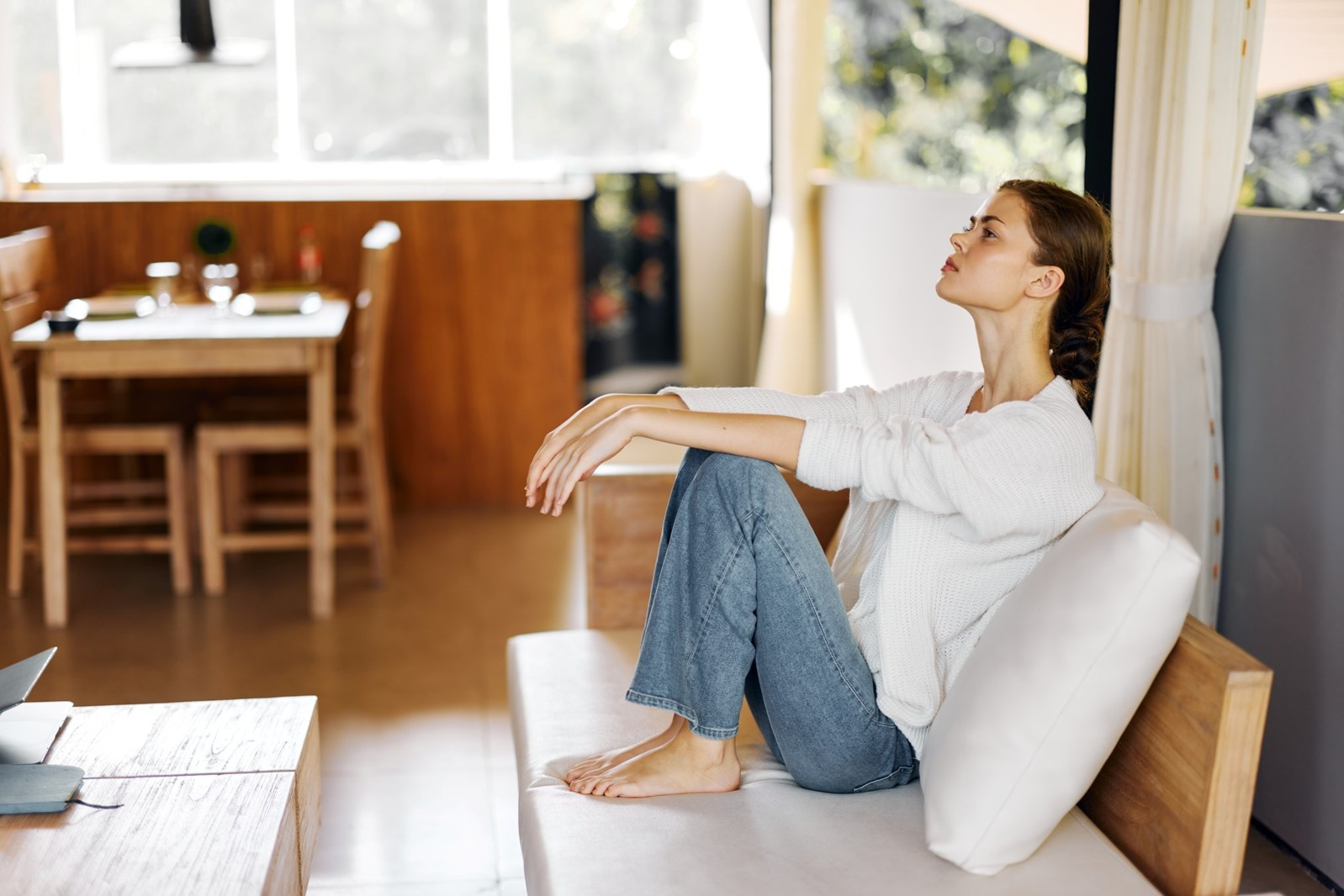 Woman sitting thoughtfully by a window, reflecting on emotions that may arise during EMDR.